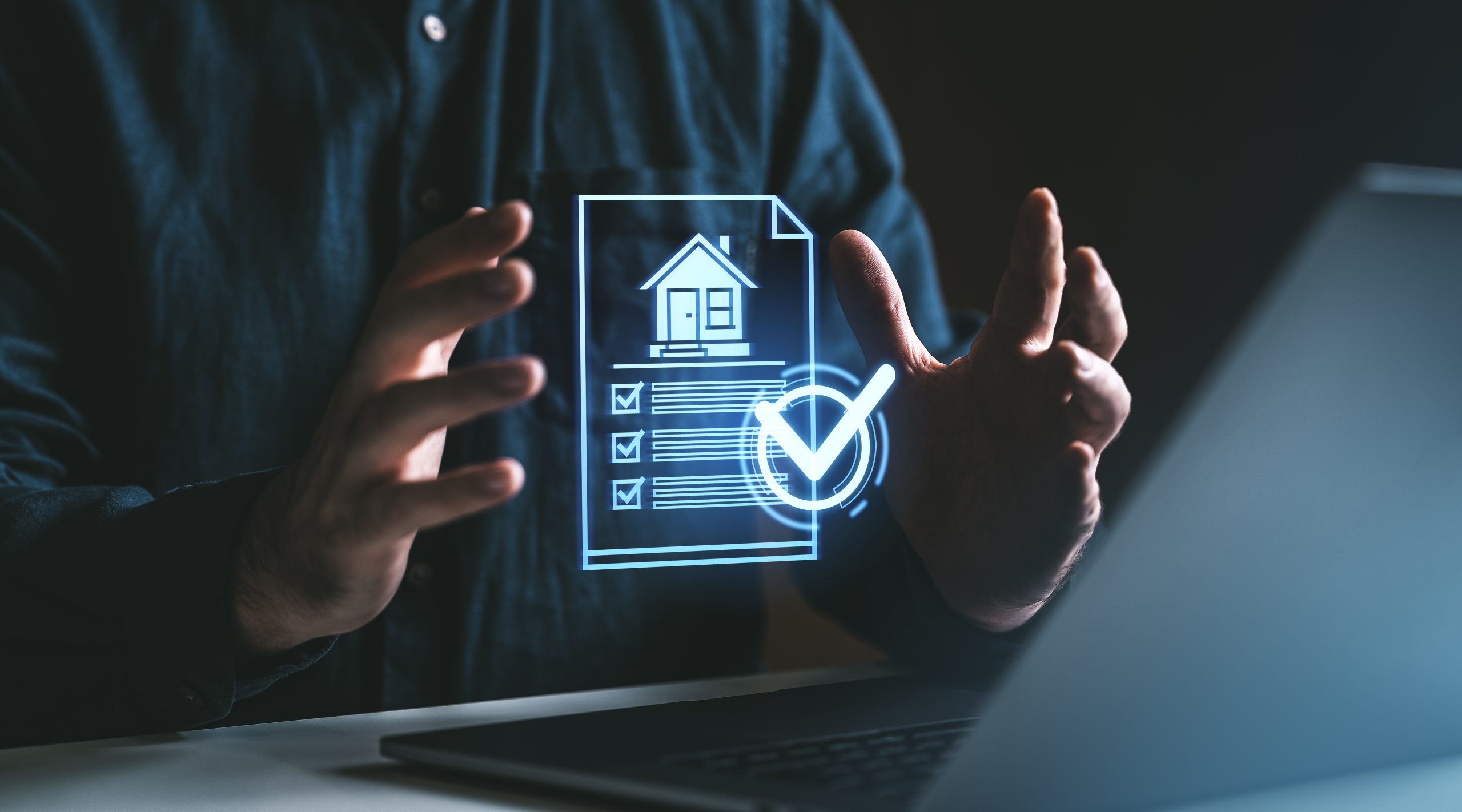 A person sitting at a desk with a laptop holds a glowing virtual document displaying a house icon, a checklist with ticked boxes, and a large check mark. The futuristic digital graphic represents property management, housing compliance, home inspections, or documentation processes.